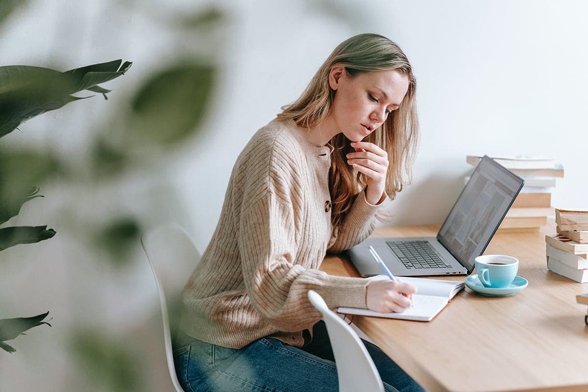 A school leader journaling at a desk, writing improvement plans alone.